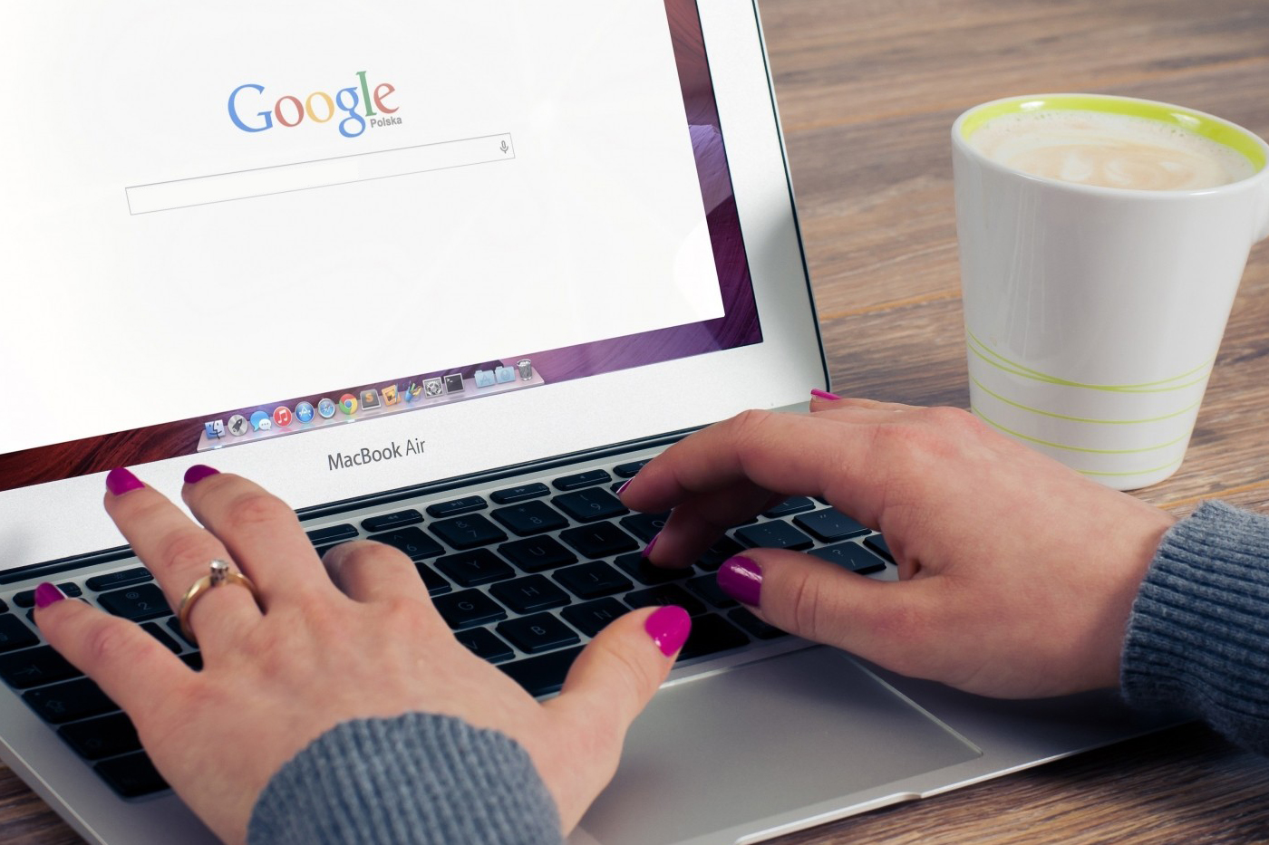 woman-sitting-at-table-and-working-on-laptop-with-coffee-mug-beside